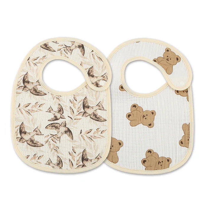 Two soft cotton baby bibs with beige trim, one featuring brown birds and leaves, the other with teddy bear prints
