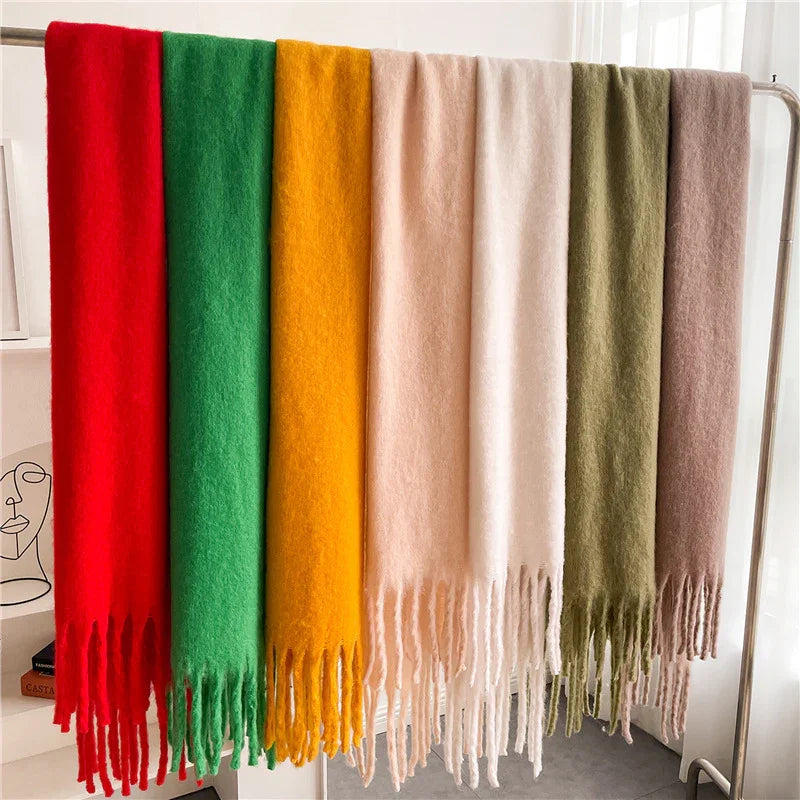 Set of seven colorful wool scarves with fringed edges hanging on a rack in a bright room