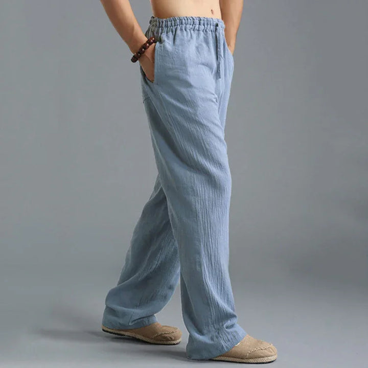 Person wearing light blue casual linen pants with elastic waist and beige slip-on shoes