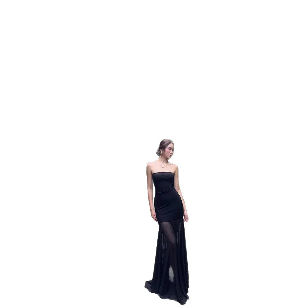 Woman wearing a strapless black evening gown with sheer long skirt posing on white background