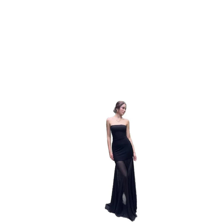 Woman wearing a strapless black evening gown with sheer long skirt posing on white background