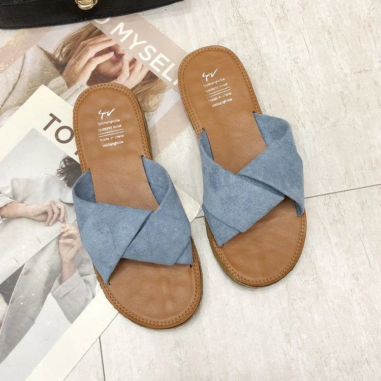 Pair of brown leather sandals with blue crisscross fabric straps on tiled floor over fashion magazines