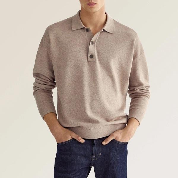 man wearing beige long-sleeve polo shirt paired with dark blue jeans against neutral background