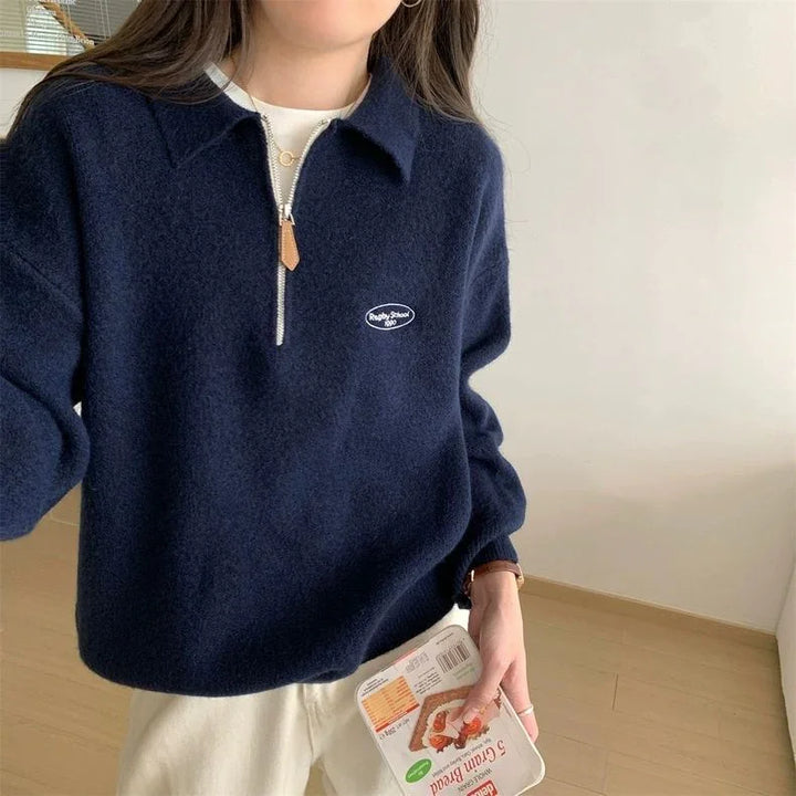Woman wearing navy blue fleece sweater with zipper and collar, holding packaged grain bread