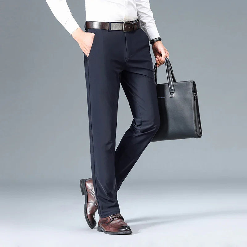 Man wearing tailored black dress pants, white shirt, brown leather belt and shoes, holding black leather briefcase