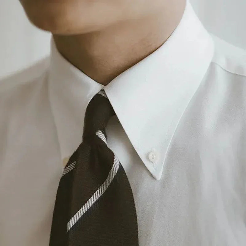 close-up of a man wearing a white dress shirt with a black striped necktie