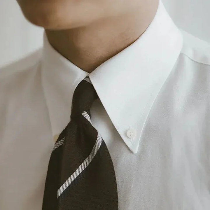 close-up of a man wearing a white dress shirt with a black striped necktie