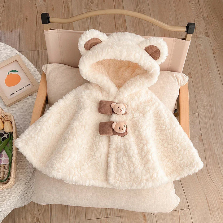 Cream fluffy baby hooded coat with teddy bear ears and buttons on beige cushion