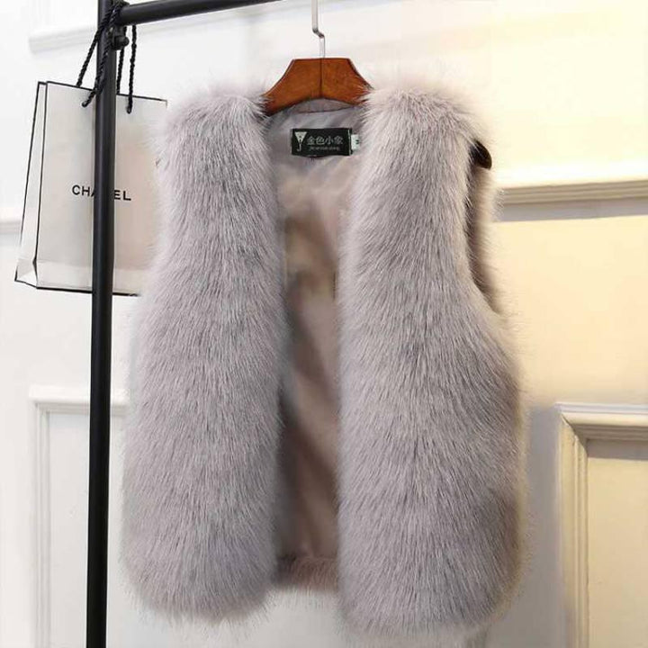 Luxurious soft light gray fur vest hanging on wooden hanger with Chanel shopping bag