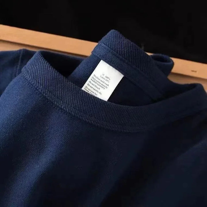 Close-up of navy blue cotton sweater collar with visible white care label on wooden surface