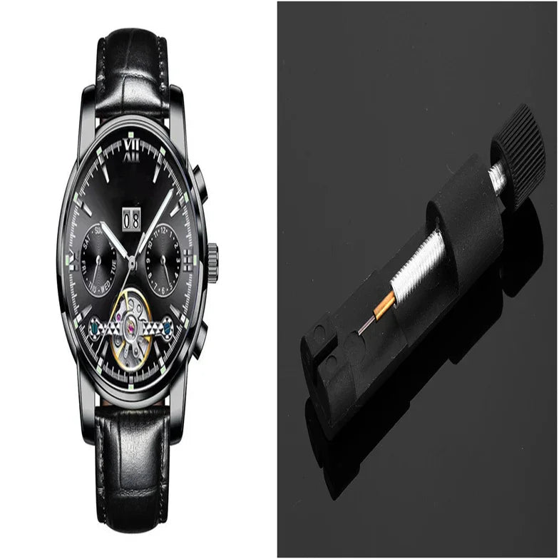 Black leather strap mechanical wristwatch with subdials and open balance wheel alongside black watchmaker tool on black surface