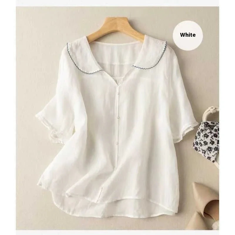 White short-sleeve blouse with scalloped collar and button front on wooden hanger