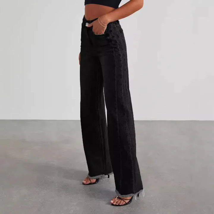 Woman wearing high-waisted black wide-leg jeans with raw hem and a black crop top