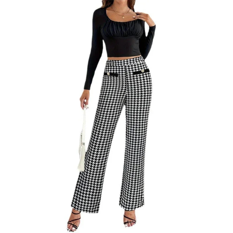 Woman in black ruched long-sleeve top and black-and-white houndstooth wide-leg pants holding white handbag