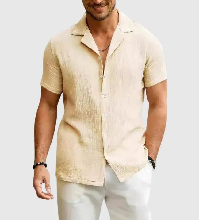 Man wearing beige short-sleeve textured button-up shirt with white pants, casual summer outfit