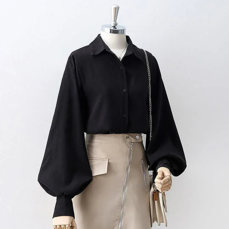 Woman's black button-up blouse with balloon sleeves paired with beige high-waist skirt and purse