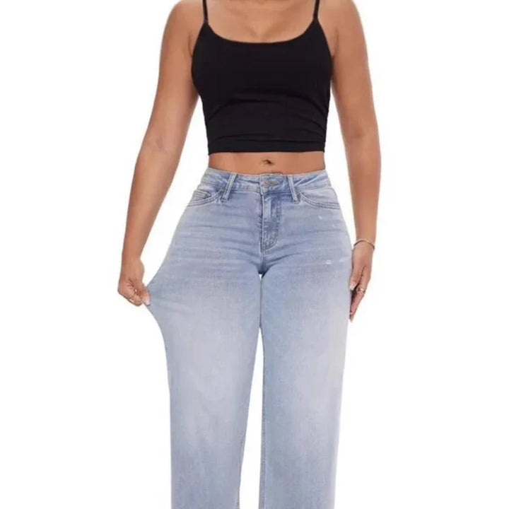 Woman wearing light blue high-waisted stretchy wide-leg jeans and a black cropped tank top