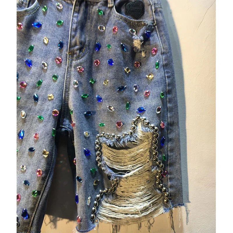 Blue denim jeans embellished with colorful rhinestones and distressed with silver bead trim