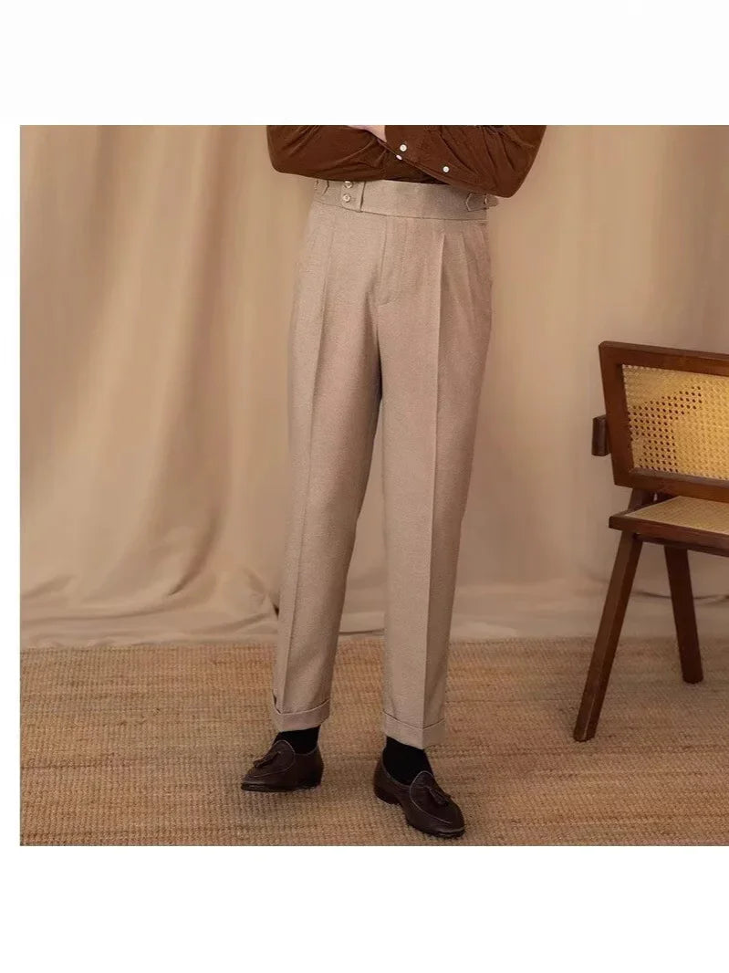 Beige high-waisted pleated trousers paired with black socks and brown tassel loafers in a neutral room
