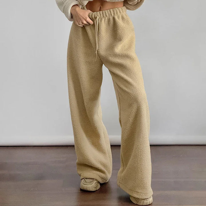 Person wearing beige sherpa fleece wide-leg pants with elastic waist and drawstring, standing indoors