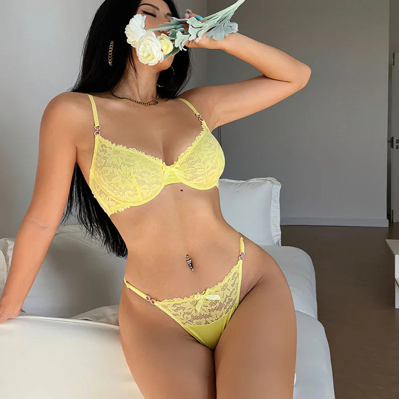 Woman in yellow lace lingerie sitting on white couch holding white and yellow flowers