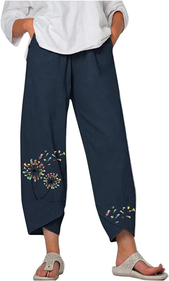 Navy blue casual pants with colorful floral dandelion embroidery on lower legs, worn with white top and sandals