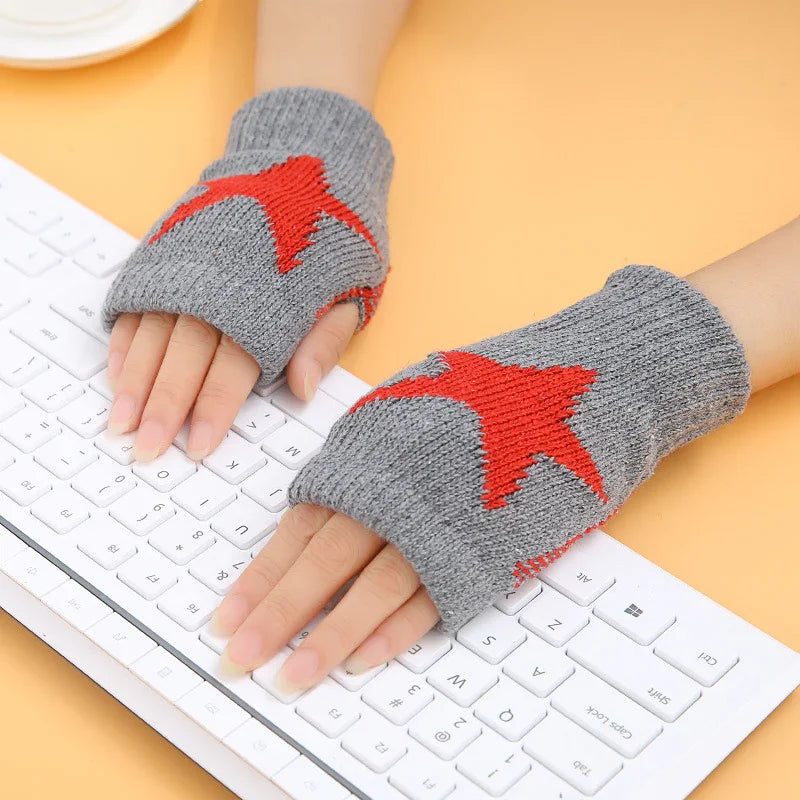 Hands wearing gray fingerless knit gloves with red star design typing on white keyboard