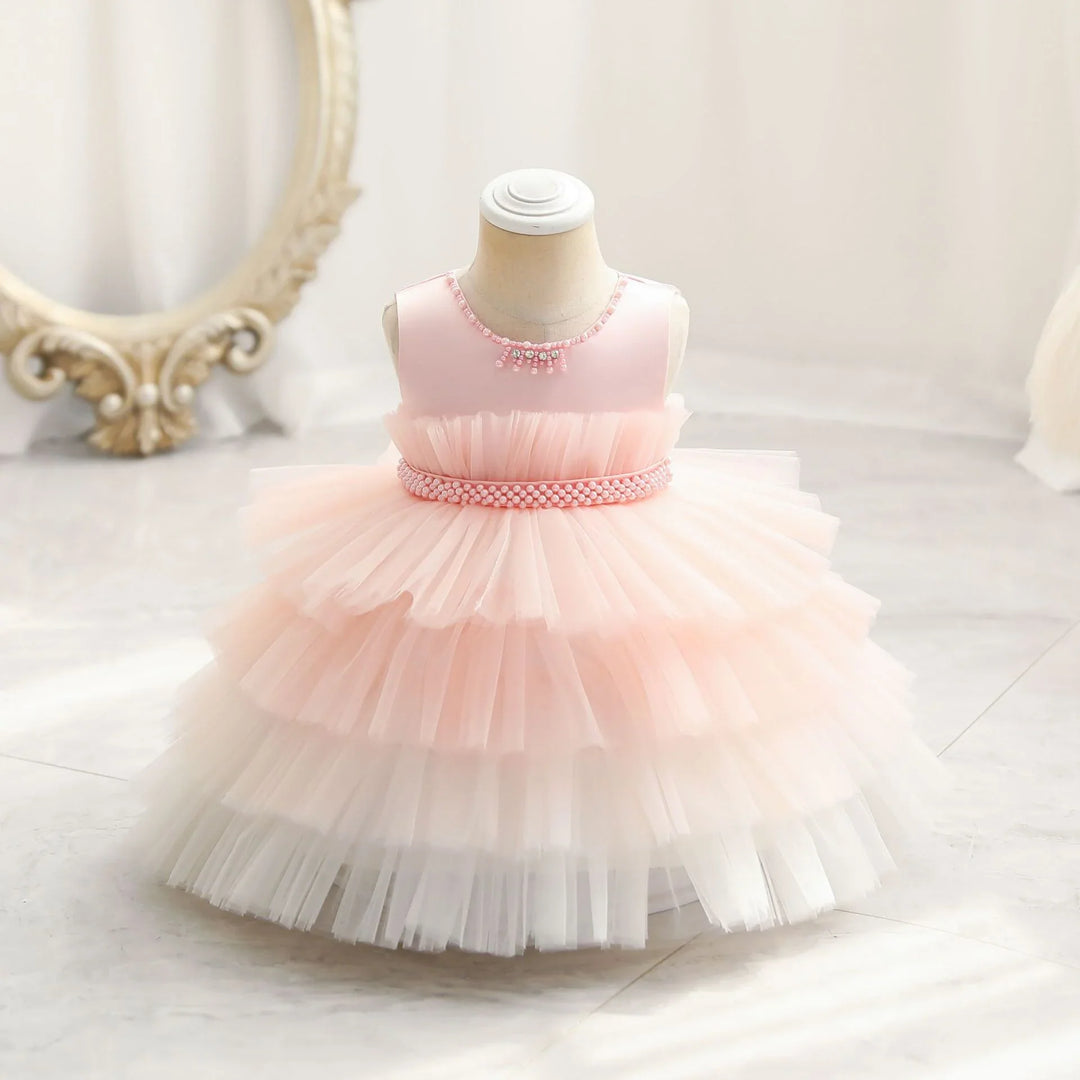 Pink and white layered tulle baby girl dress with pearl bead details on mannequin