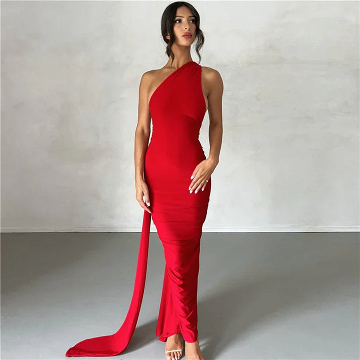 Woman wearing a red one-shoulder fitted evening gown with a long sash and nude heels