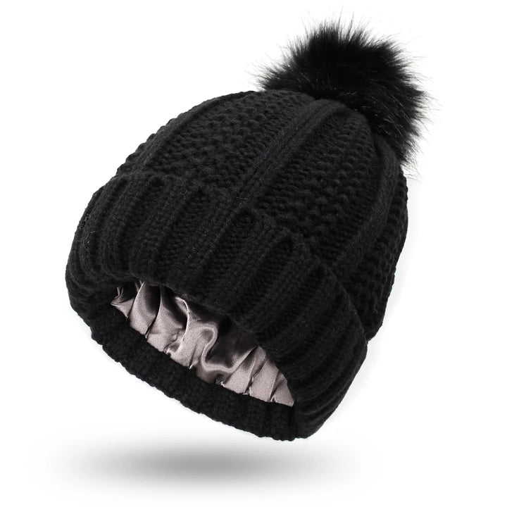Black knitted beanie hat with pom pom and satin-lined interior for winter wear