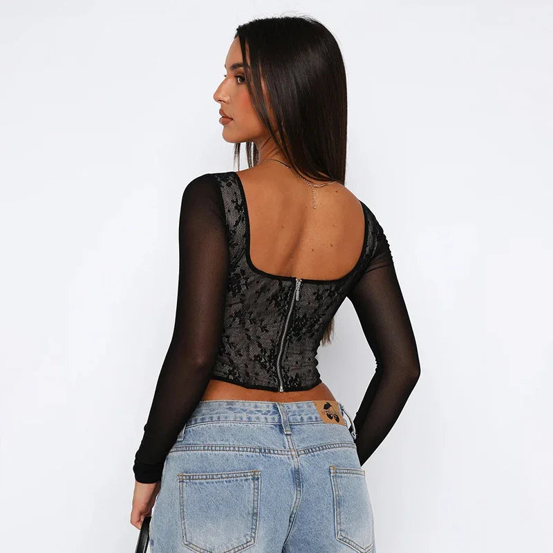 Woman facing backward wearing black lace mesh top with zipper and light blue high-waisted jeans