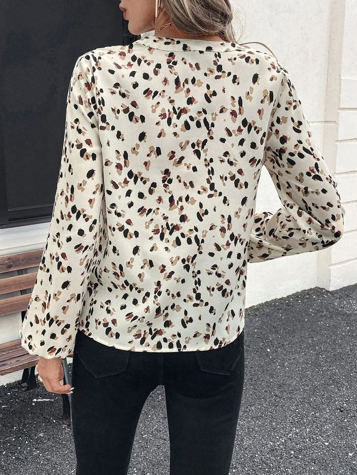 Woman wearing cream long-sleeve blouse with brown and black leopard print, paired with black pants