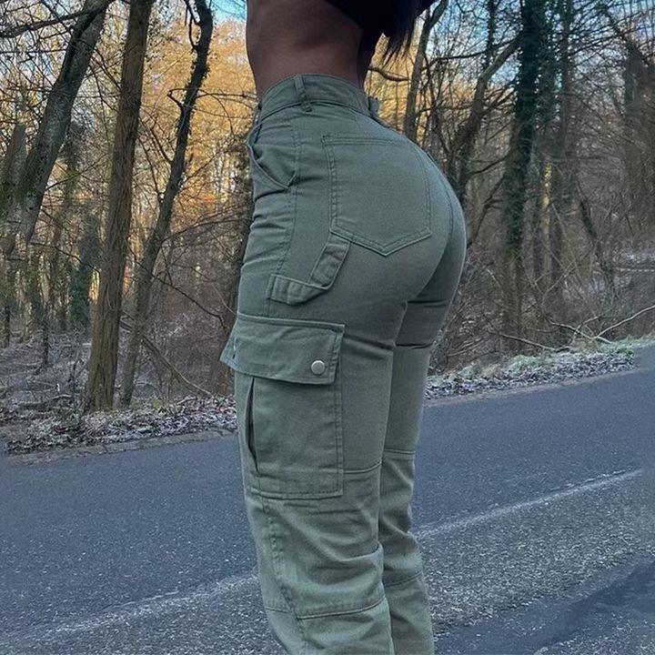 Person wearing high-waisted olive cargo pants on a road with forest trees in the background