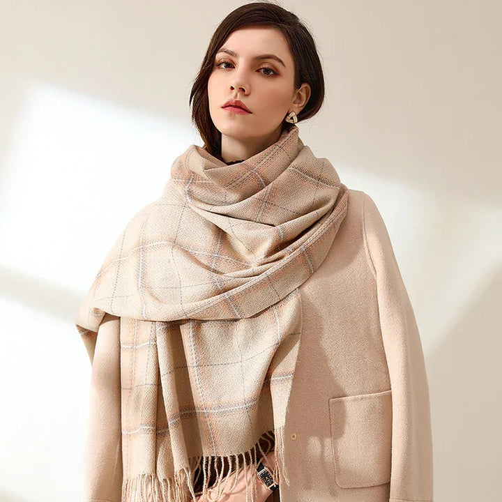 Woman wearing beige wool coat and large plaid scarf with fringes in soft natural light