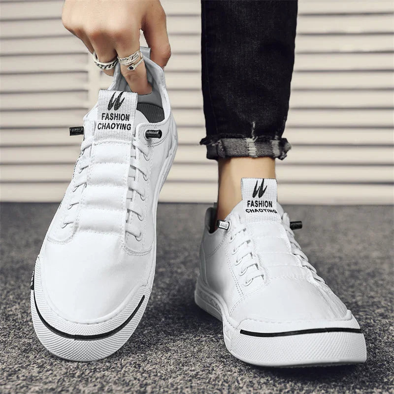 White casual sneakers with black trim and FASHION CHAOYING branding worn with rolled black jeans on textured ground