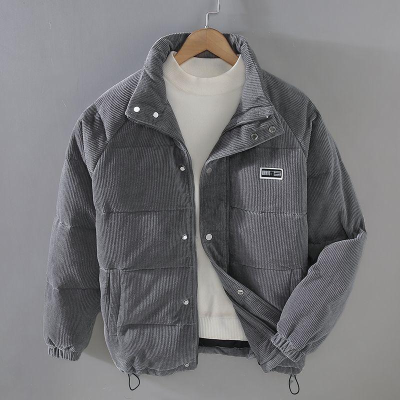 Gray corduroy puffer jacket with snap buttons on hanger over white turtleneck sweater