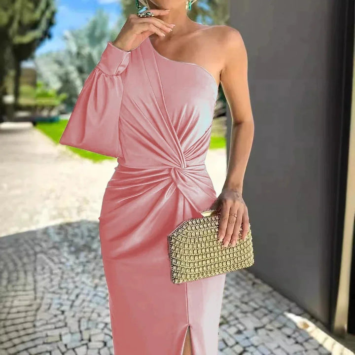Woman wearing pink one-shoulder ruched midi dress holding gold rhinestone clutch outdoors
