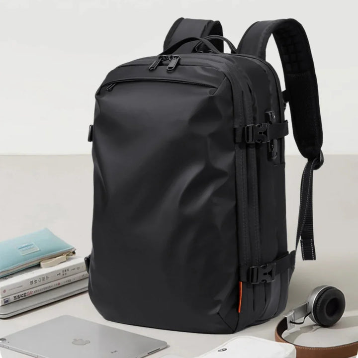 Sleek black modern backpack with multiple compartments, laptop, books, and headphones on desk