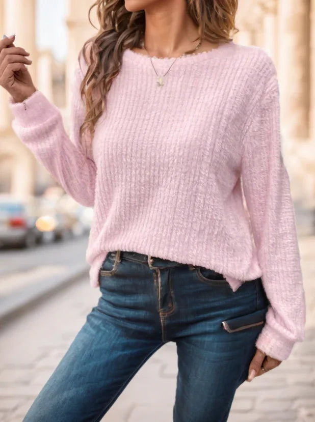 Woman wearing a soft pink fuzzy sweater paired with blue denim jeans on a city street