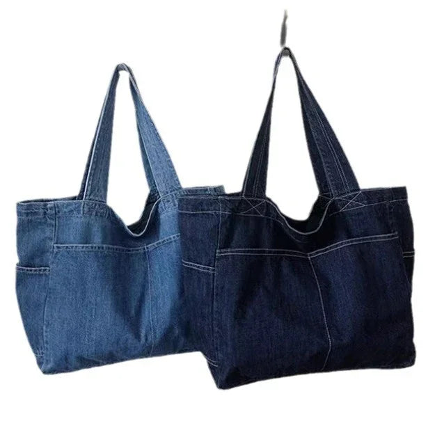 Two denim tote bags, one light blue and one dark blue, hanging side by side on white background