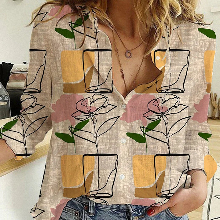 Woman wearing a button-up shirt with abstract floral and geometric pattern in yellow, pink, green