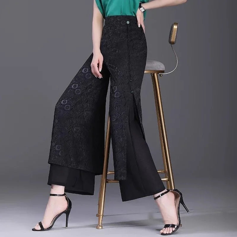 Woman wearing black floral lace overlay wide-leg pants with front slit and black high heel sandals