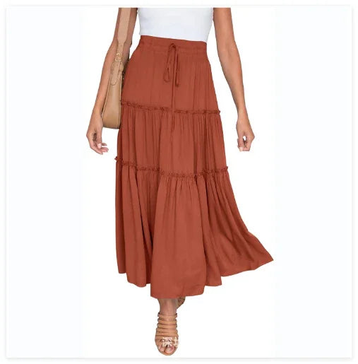woman wearing rust red tiered maxi skirt with drawstring waist and white top, tan sandals and handbag