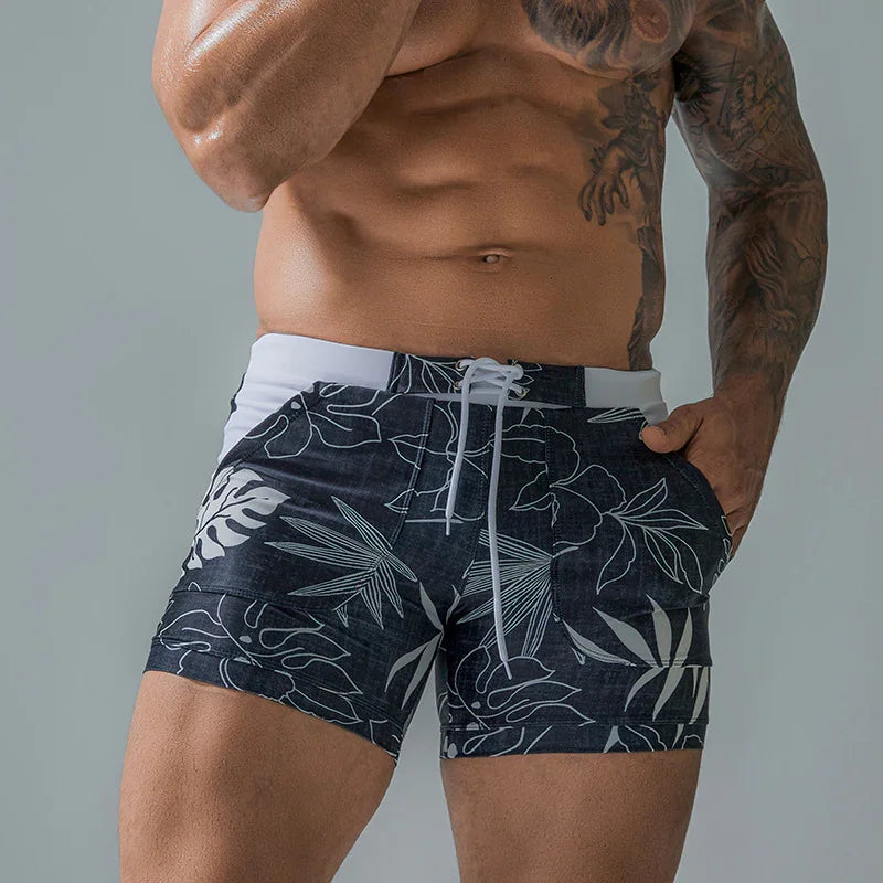 muscular man wearing black and white floral print swim trunks with drawstring waist