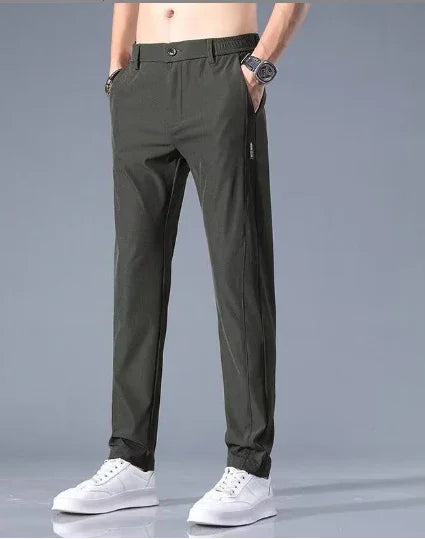 Men's casual black slim-fit pants paired with white sneakers against gray background