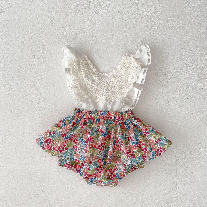 Baby romper with white lace top and colorful floral skirt on white background