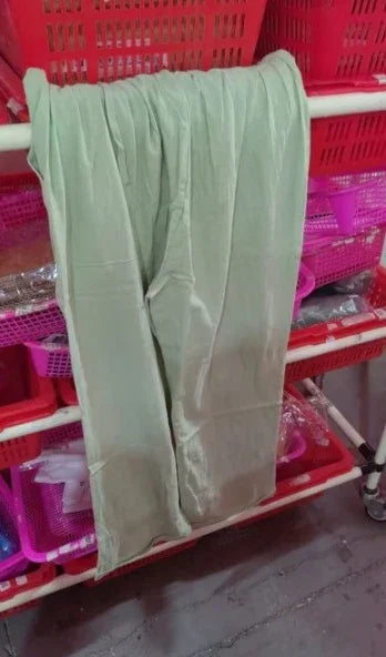 Light green pants hanging on white rod with red and pink plastic baskets in background