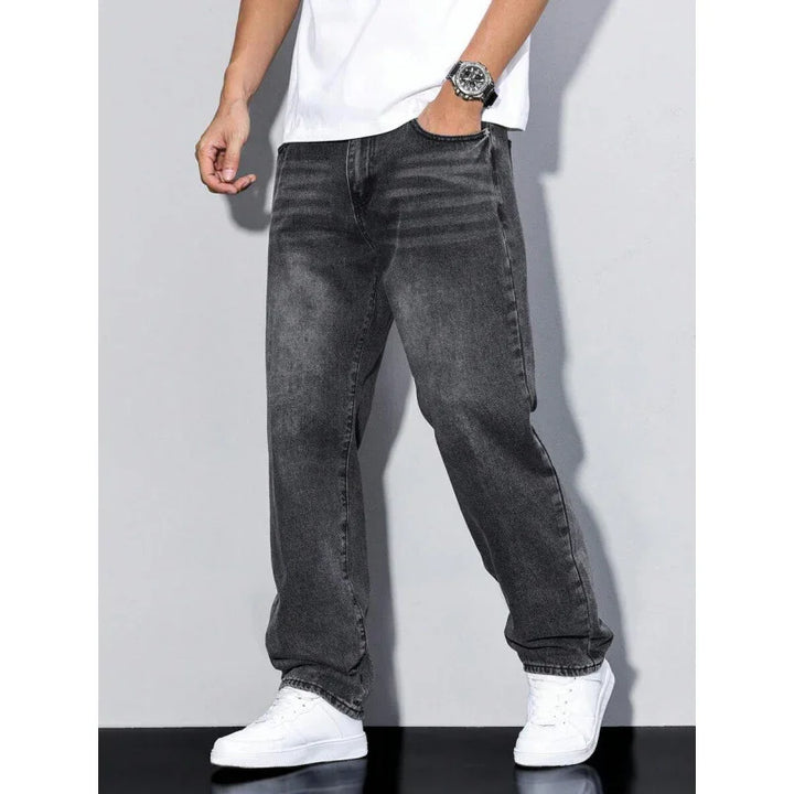 Men's casual black washed jeans paired with white sneakers and a white t-shirt against a gray background