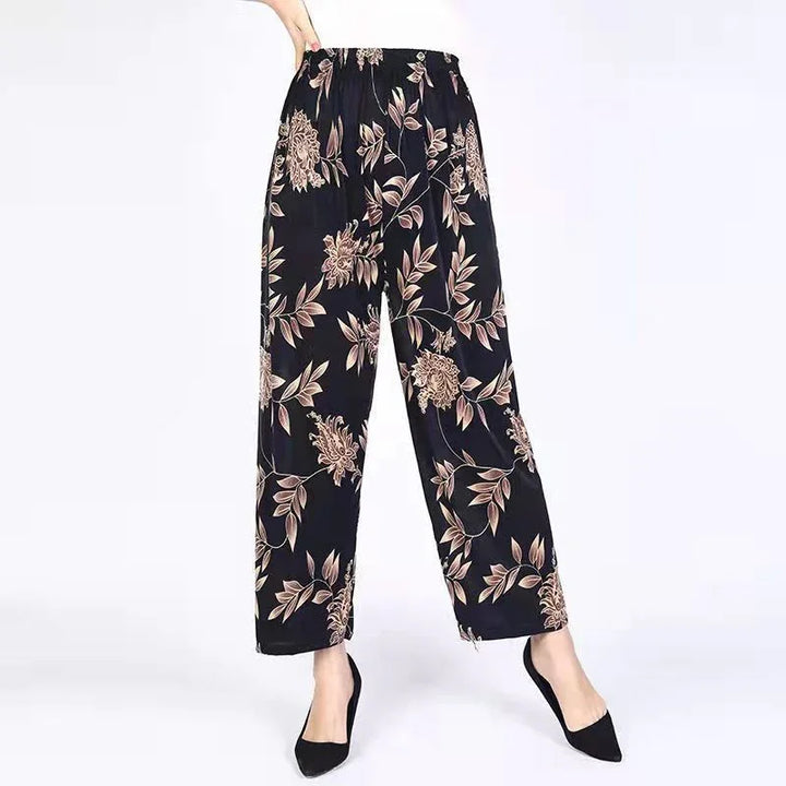 Black wide-leg pants with beige floral print, elastic waist, worn with black pointed shoes