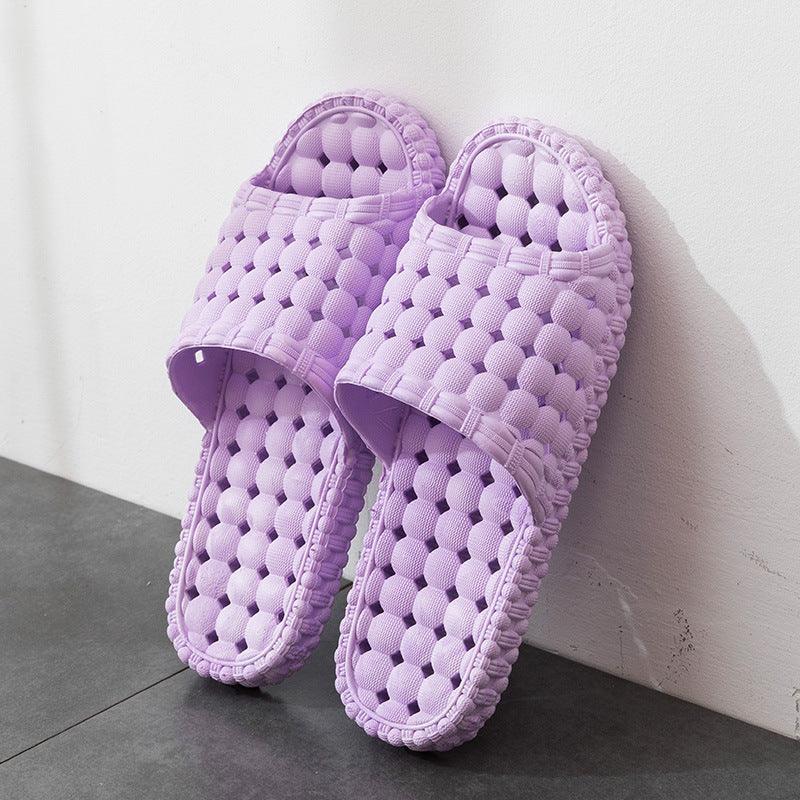 Pair of lavender purple textured bubble design slip-on indoor slippers on gray floor